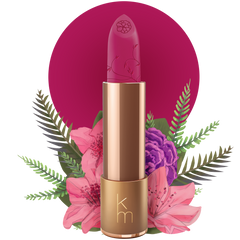 A gold-colored tube of natural lipstick with a fuchsia color bullet, adorned with a floral illustration. The brand's initials 'km' are visible on the lipstick tube.