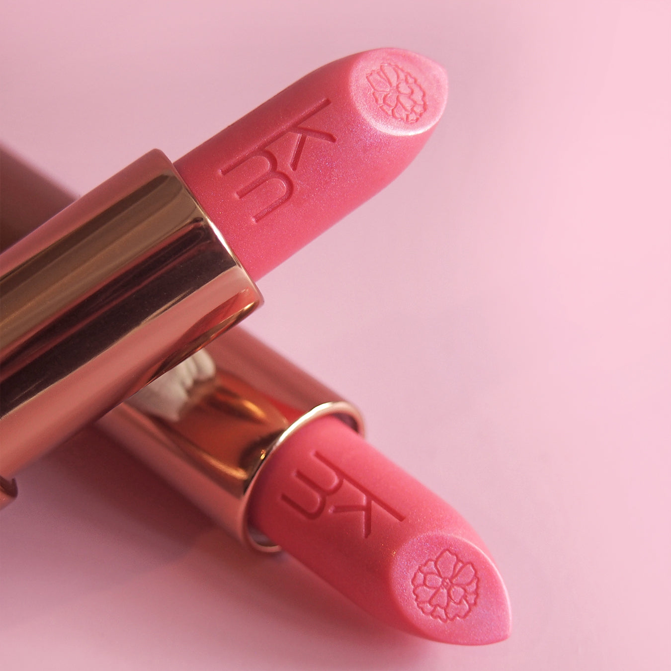 Pink lipstick with gold cap on a pink background